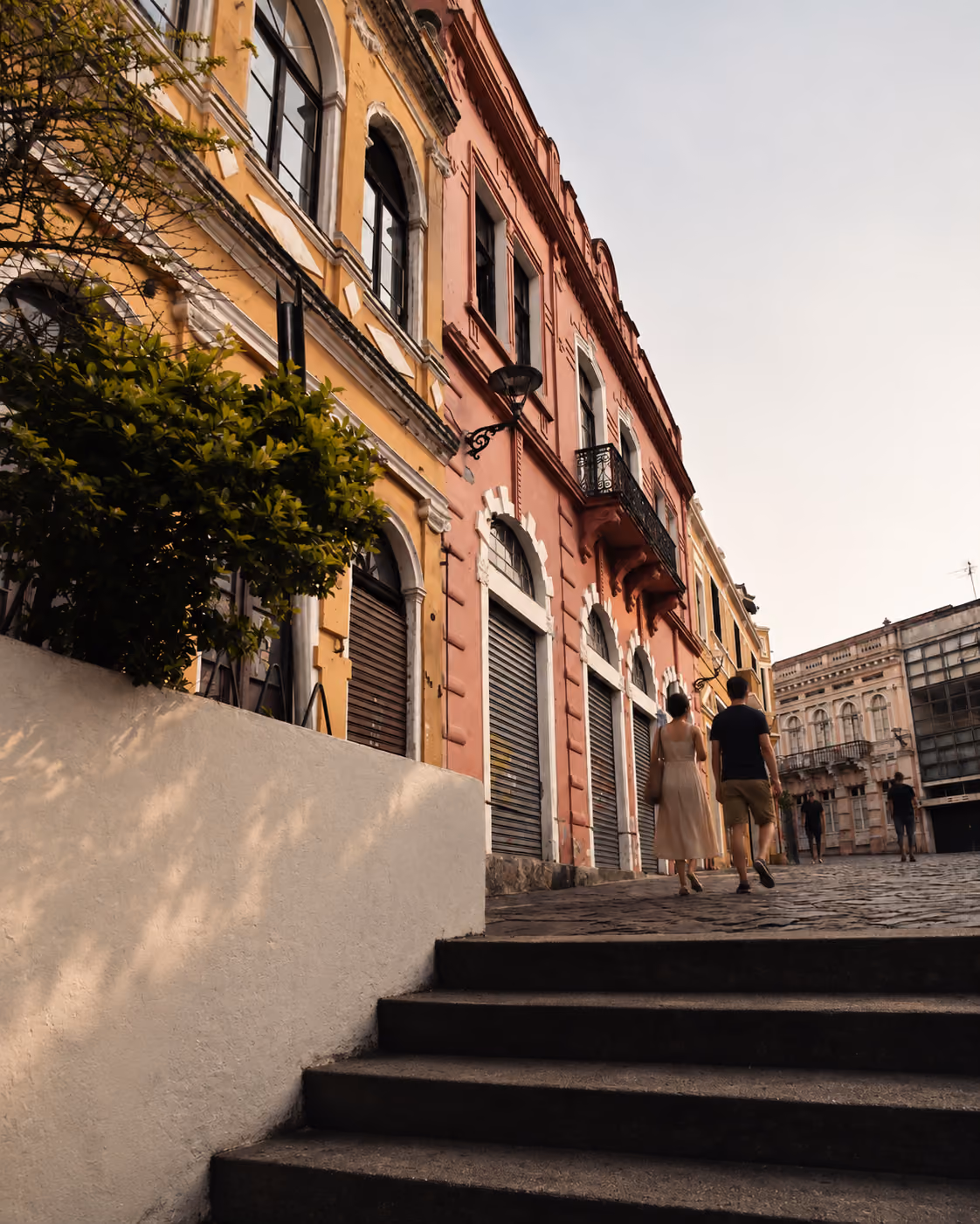 Casal caminhando entre casarões históricos no Largo da Ordem, em Curitiba